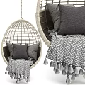 Rattan Egg Shaped Hanging Chair With Gray Cushions And Fringed Blanket