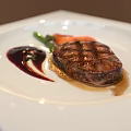 Grilled Steak Plated with Green Vegetables Carrots and Red Sauce on White Square Plate