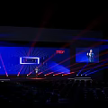 TEDx Conference Stage Featuring Speaker Large Screen Red Blue Laser Lights And Audience