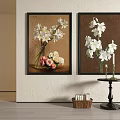 Two Framed Floral Paintings With White Flowers Vases Candles Small Table Woven Basket And Bottles