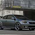 Gray Modified Car With Rear Spoiler And Large Alloy Wheels Parked At Concrete Garage Entrance