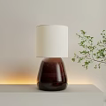 Modern Table Lamp with White Lampshade and Dark Base on Light Tabletop with Green Plant