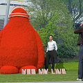 Giant Red Plant Shaped Garden Ornament with People Taking Photos in Outdoor Park