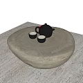 Round Stone Coffee Table With Black Teapot And Two Small Teacups On Woven Rug