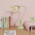 Transparent Petal Shaped Table Lamp With Green Stem Base And Books Alarm Clock On Desk