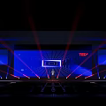 TEDx Conference Stage Featuring Speaker Large Screen Red Blue Laser Lights And Audience