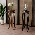 Wooden Plant Stands with Carved Design Holding Flower Vase and Decorative Statue Near Green Plant