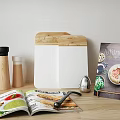 Essential Kitchen Utensils on Wooden Tabletop with Open Magazine Pepper Grinders Cutting Board and Cookbook