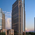 Modern High Rise Office Building With Glass Facade And Illuminated Windows At Sunset
