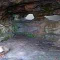 Natural Rock Cave Landscape Featuring Overhead Openings Mossy Ground and Rocky Formations