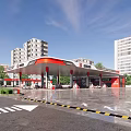 Modern Gas Station With Red White Canopy Fuel Pumps And High Rise Buildings At Dusk