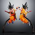 Two Anime Character Statues in Jumping Pose with Orange Clothing Black Hair Holding Red Staff