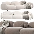 Plush Neutral Colored Three-Seater Sofa With Cozy Blanket And Round Decorative Pillows