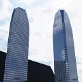 Two Tall Office Buildings With Glass Curtain Walls Against Blue Sky And White Clouds