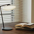 Modern Minimalist Table Lamp on Wooden Table with Open Book and Window Blinds