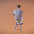A Man Sitting On Stool Holding Phone Wearing Gray Long Sleeve Shirt And Light Pants