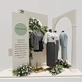 Mannequins Wearing Simple Classic Clothes In Display Area With Green Plants And Flower Decorations