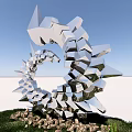 Modern Metal Art Installation With Spiral Shapes Reflective Surfaces On Grass Base With Stone Accents