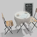 Round Table with Wooden Chairs Checkered Tablecloth Cups Open Book and Chalkboard Sign