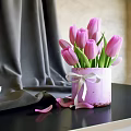 Pink Tulips In Purple Pot With White Ribbon On Gray Fabric Background And Scattered Petals