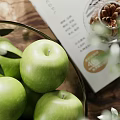 Ceramic Bowl Filled With Fresh Green Apples And Olive Branches Along With Walnuts On Wooden Table