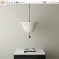 White Bell Shaped Pendant Light With Green Ball Above White Table And Books