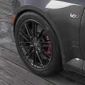 Car Tire With Black Alloy Wheels Red Brake Calipers And Tread Pattern On Wooden Deck