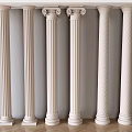 White Decorative Columns In Various Styles Against Light Wall And Wooden Floor