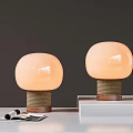 Round Peach Colored Shade Table Lamps With Woven Brown Base On White Table And Magazines