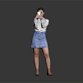 A Woman Wearing White Shirt And Blue Denim Skirt Using Smartphone Against Gray Reflective Floor