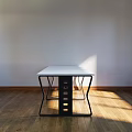 Modern Office Desk With White Top And Black Curved Legs On Wooden Floor In Sunlight
