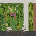 Lush Green Plant Wall With Various Plants Flowers And White Chairs In Indoor Space