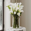 White Calla Lilies Arranged In Transparent Glass Vase On Black Table