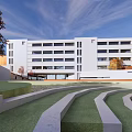 Modern School Building Featuring White Exterior Multiple Floors Large Windows And Trees In Open Square