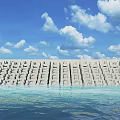 Rock Seawall Extending Along Calm Ocean Under Blue Sky With White Clouds