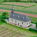 Aerial View Of Green Countryside Farmland With Historic Church And Lush Trees