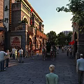 Traditional Style Commercial Street With Pedestrians Outdoor Seating And Cultural Signs