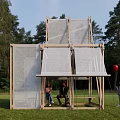 Modern Wooden Pergola With Mesh Panels On Grass At Sunset With People And Red Balloon