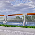 Roadside Railing Fence Along Waterfront With Green Grass Trees And Cloudy Sky