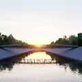Scenic Landscape Bridge Over Calm Water With Sunset Reflection And Green Trees Under Twilight Sky