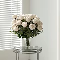 Fresh White Roses Floral Arrangement In Glass Vase On Round Table By White Window Blinds