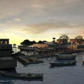 Ancient Buildings Along Waterfront With Boats On Water Sunset Sky And Distant Hills Trees