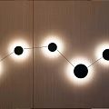 Modern Black Circular Wall Lamp in Curved Arrangement on Wooden Wall with Warm Glowing Light