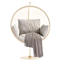 Round Golden Frame Hanging Chair With White Cushions And Gray Blanket