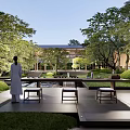 Tranquil Courtyard Garden with Person Standing Among Lush Trees Green Lawn Water Pond and Stone Benches