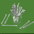 White Cotton Swabs in Transparent Glass Cup and Scattered on Green Background