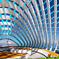 Modern Pergola With Blue And White Striped Curved Structure Wooden Platform And Greenery