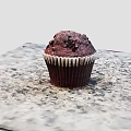 Freshly Baked Chocolate Muffin With Paper Liner And Crumbly Top On Marble Countertop