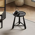Minimalist Black Round Side Table with Teapot Tray Near Wicker Chair on Herringbone Floor