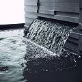 Modern Garden Water Feature With Flowing Water From Black Wall Into Pool